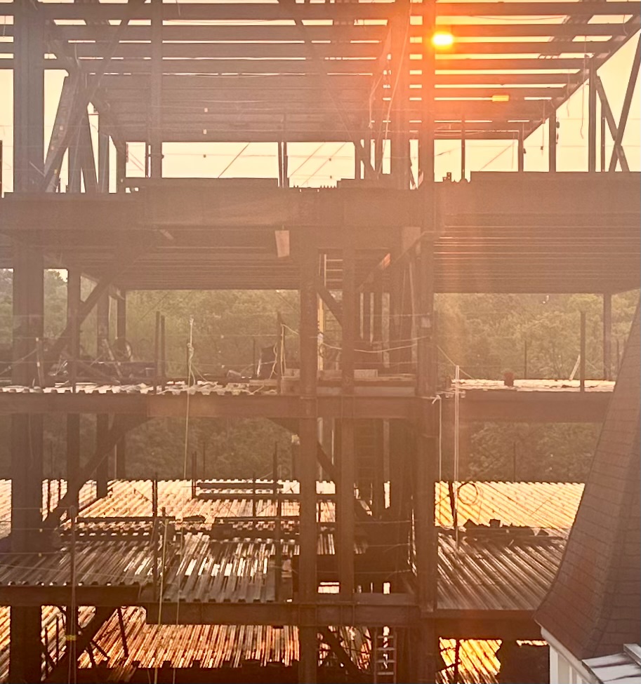 Sunset glowing through framework of a city building under construction.