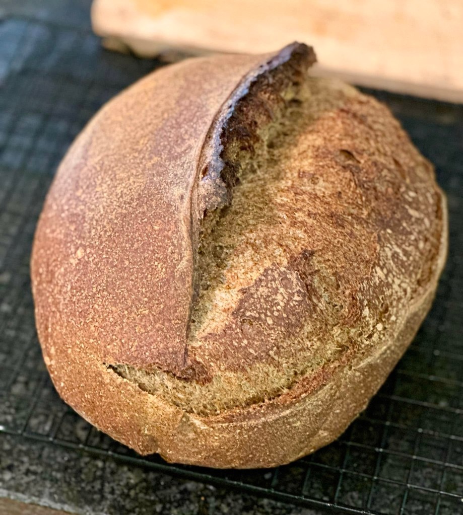 Dark crusted Guinness and buckwheat sourdough loaf cooling on a rack.