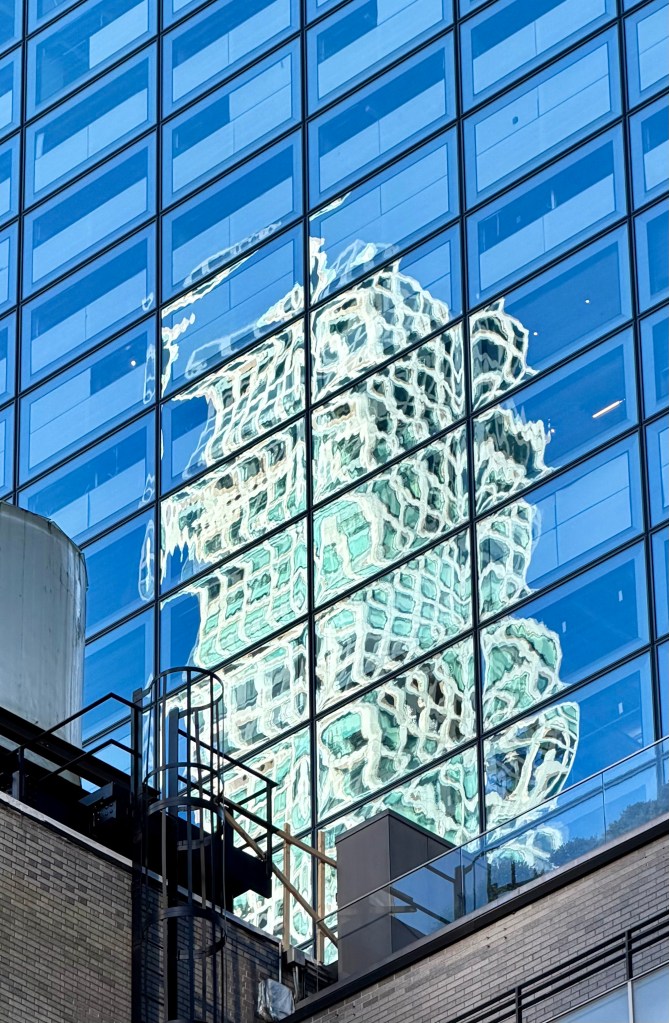A reflection of 432 Park Avenue and 57th Street in an adjacent glass walled building as seen from the courtyard of the MoMA.