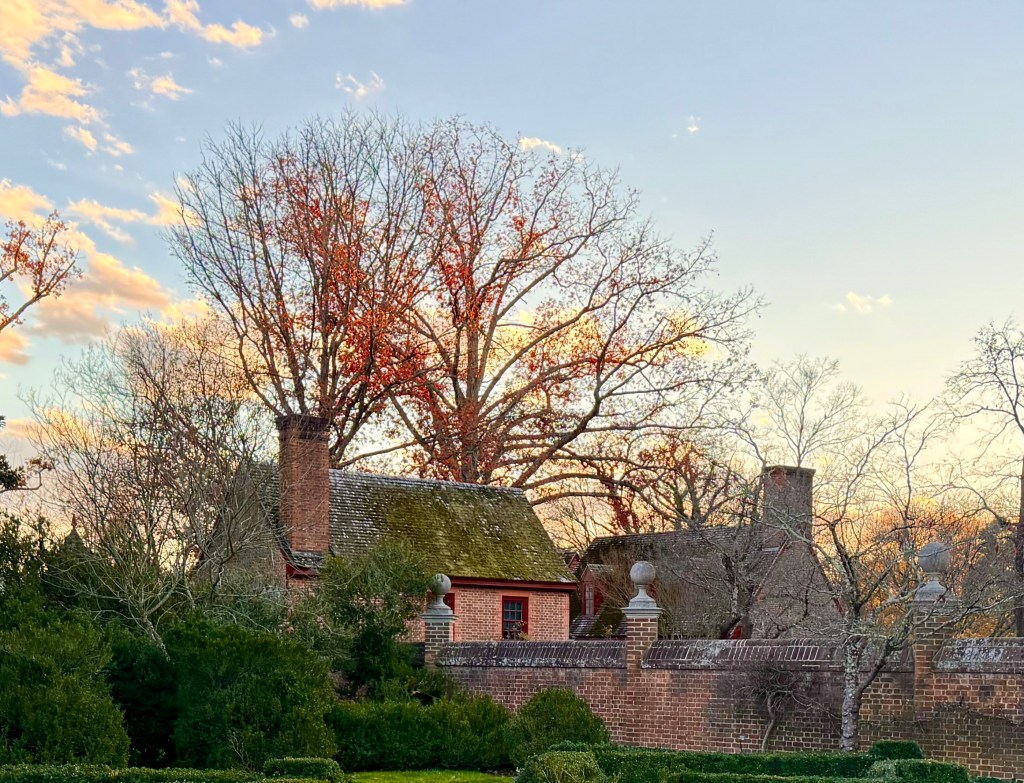 Two small brick houses with moss covered roofs on the Palace Green at Colonial Williamsburg as seen from Inside the walls of the Governor's Palace.