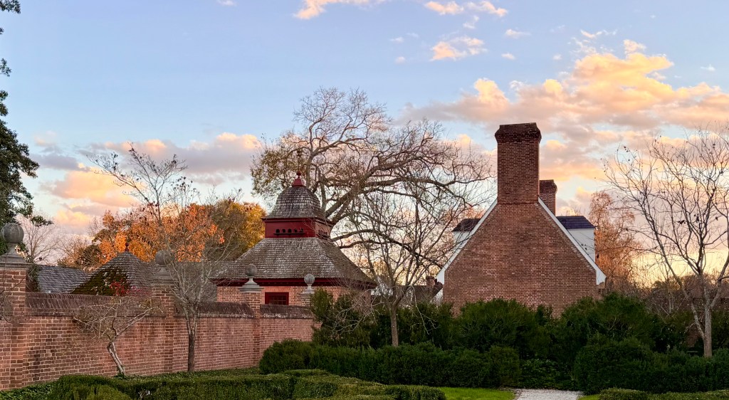Red brick outbuildings in the Governor's Palace stable yard at Colonial Williamsburg as seen from inside the Palace walls.