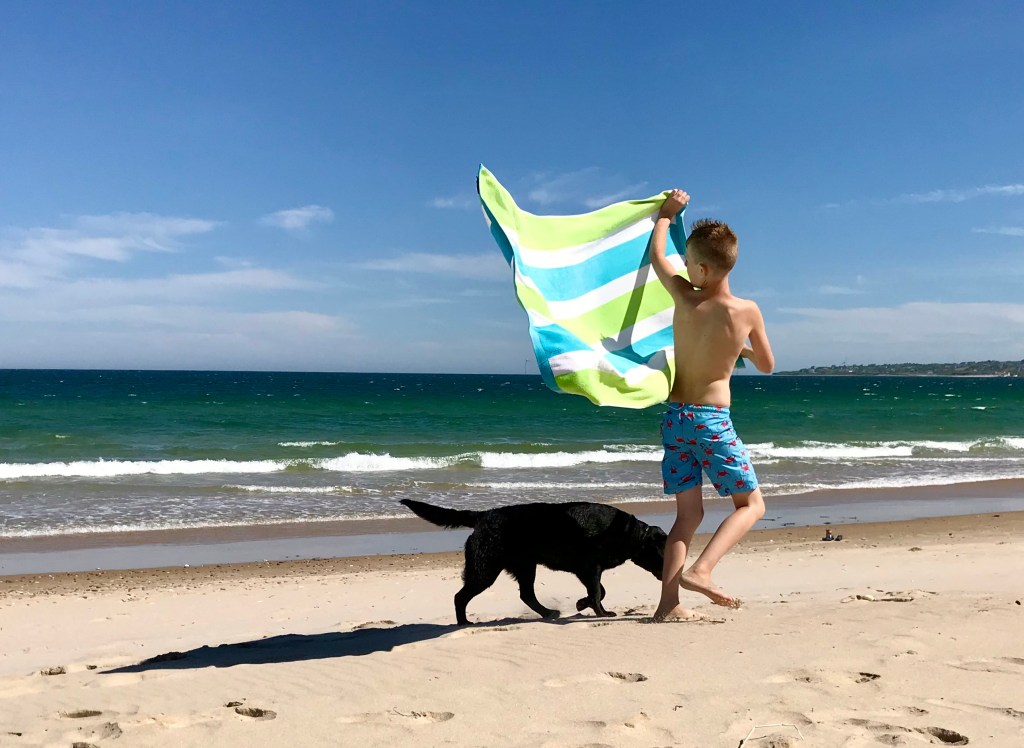 A boy and his dog on a windy day at Mansion Beach - Block Island, Rhode Island.