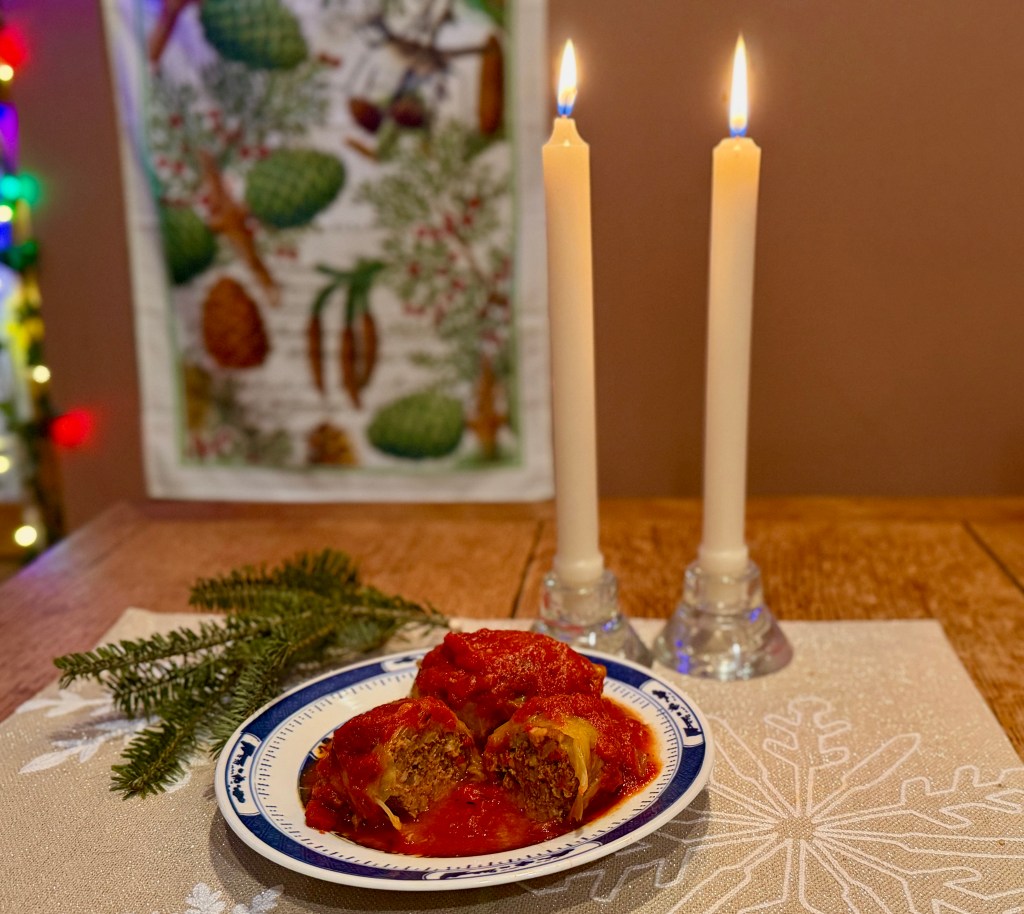Traditional stuffed cabbage rolls served on blue and white china on an old farmhouse table set for New Year's Day dinner.